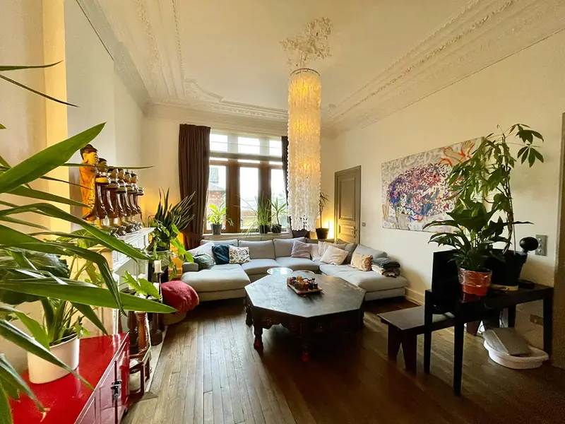 Het salon van Villa O met kunst, planten en Art-Nouveau-plafonds